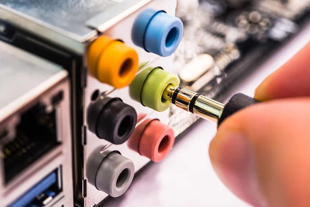 Six connecteurs mini-jack de couleurs différentes, avec une fiche insérée dans le connecteur vert